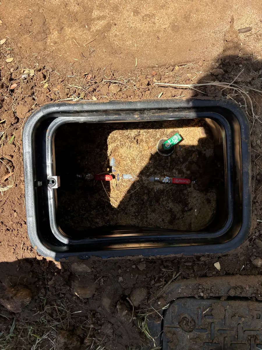 In-ground valve box housing a brass shut-off and backflow assembly on a residential water line