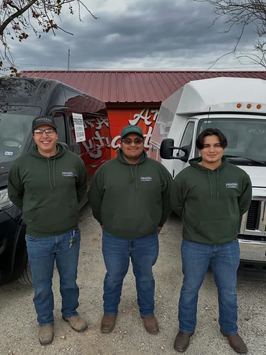 Three Proverbs Plumbing technicians in branded hoodies standing in front of the company service vans