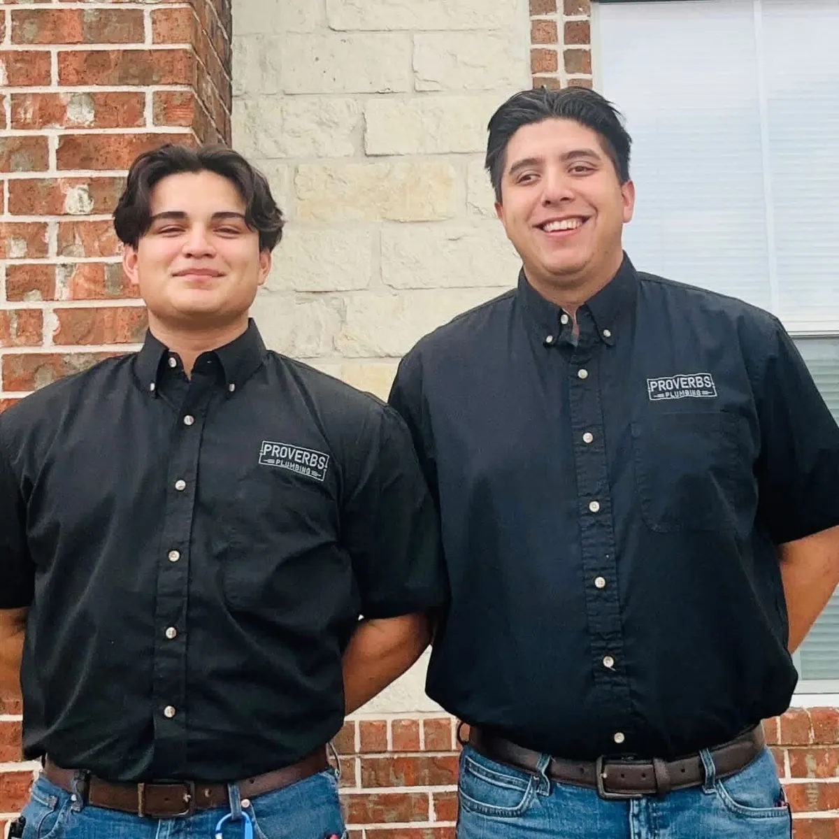 Two Proverbs Plumbing technicians in branded button-up shirts outside a Central Texas home