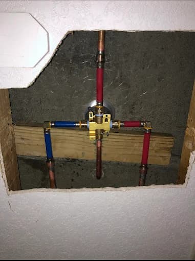 Shower mixing valve roughed in with copper risers and PEX supply lines inside an open wall