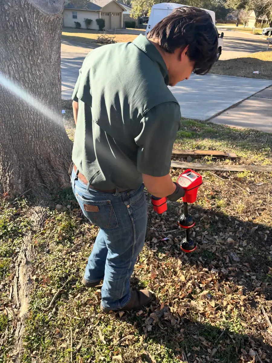 Proverbs Plumbing technician tracing an underground line with a handheld pipe locator in a front yard