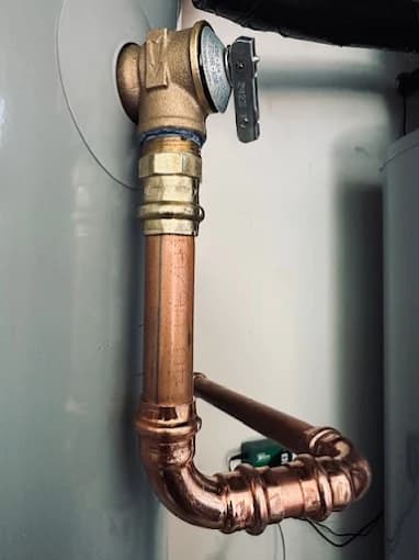 Newly soldered copper supply lines and brass shut-off valve at the top of a water heater